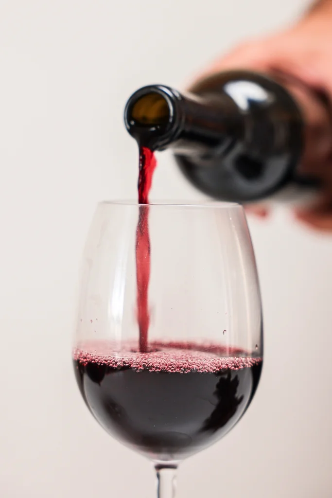 sirviendo una copa de vino tinto